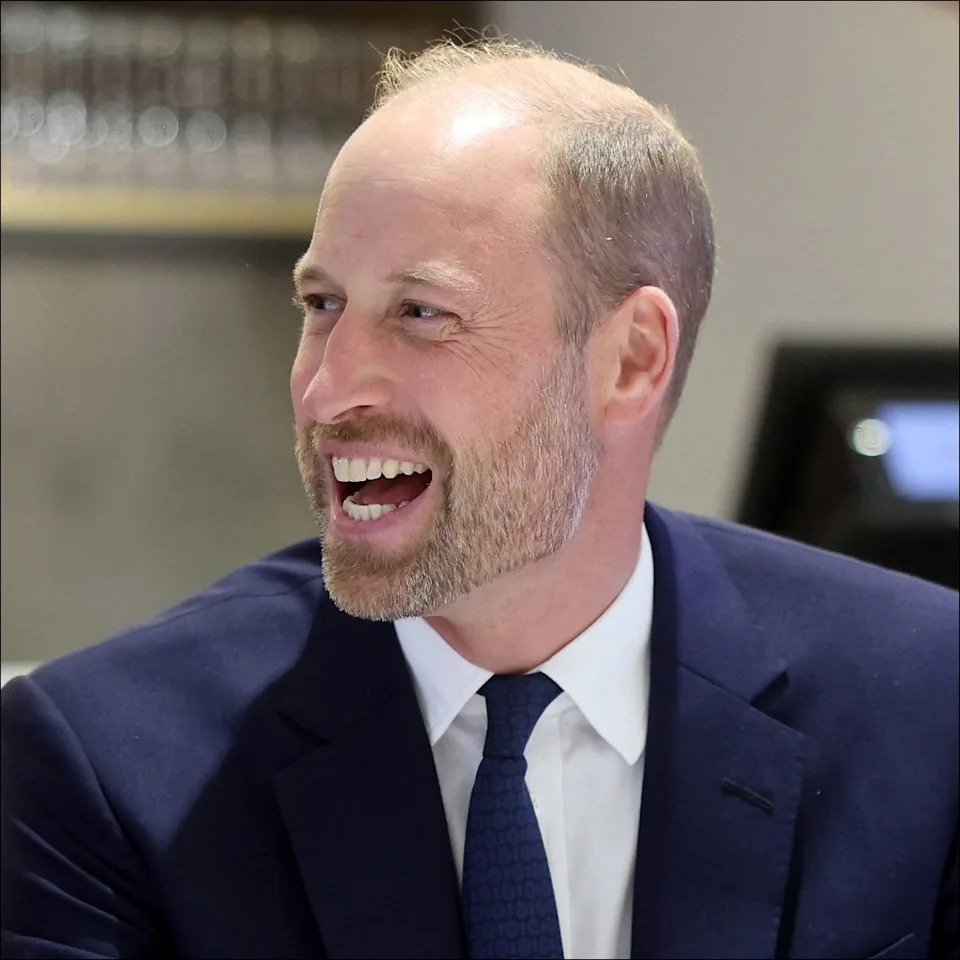  Prince William wears a navy suit and laughs. 