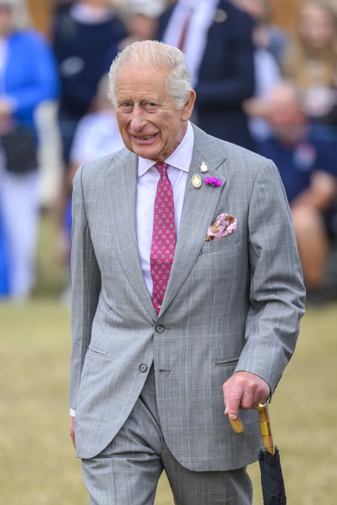 King Charles walking and smiling in grey suit