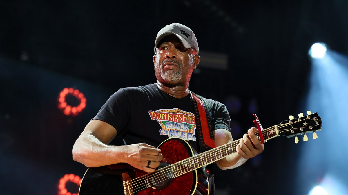Darius Rucker plays the guitar on stage