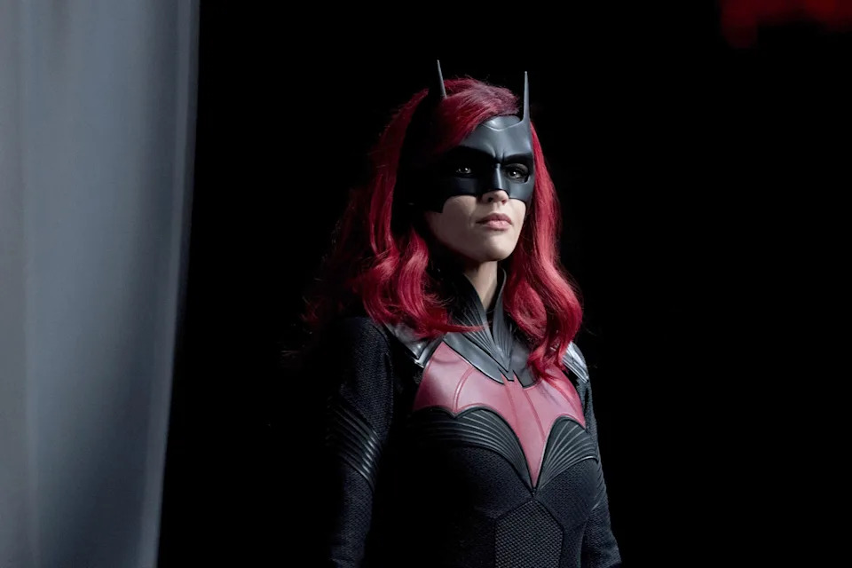A person in a superhero costume with bat-like mask and emblem, looking determined