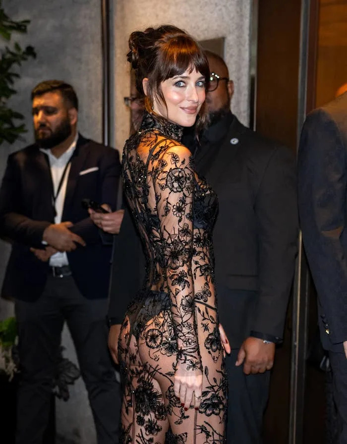 Dakota Johnson on a red carpet wearing a sheer floral lace dress