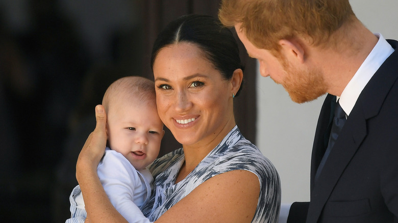 Meghan Markle holds Prince Archie while standing next to Prince Harry