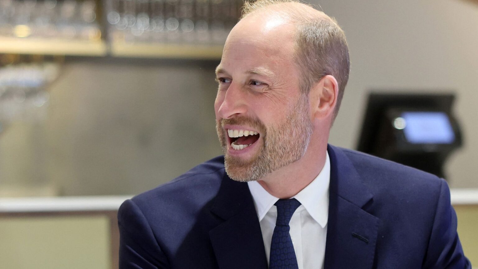 Prince William wears a navy suit and laughs