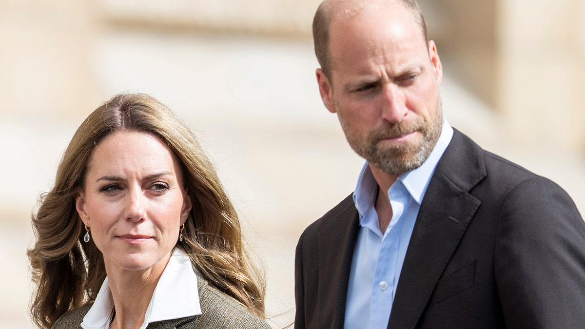 Prince William and Kate Middleton walking together looking serious.