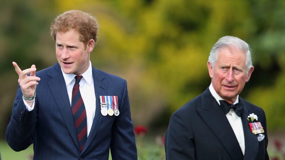 A young Prince Harry in a suit pointing as his father King Charles looks on.