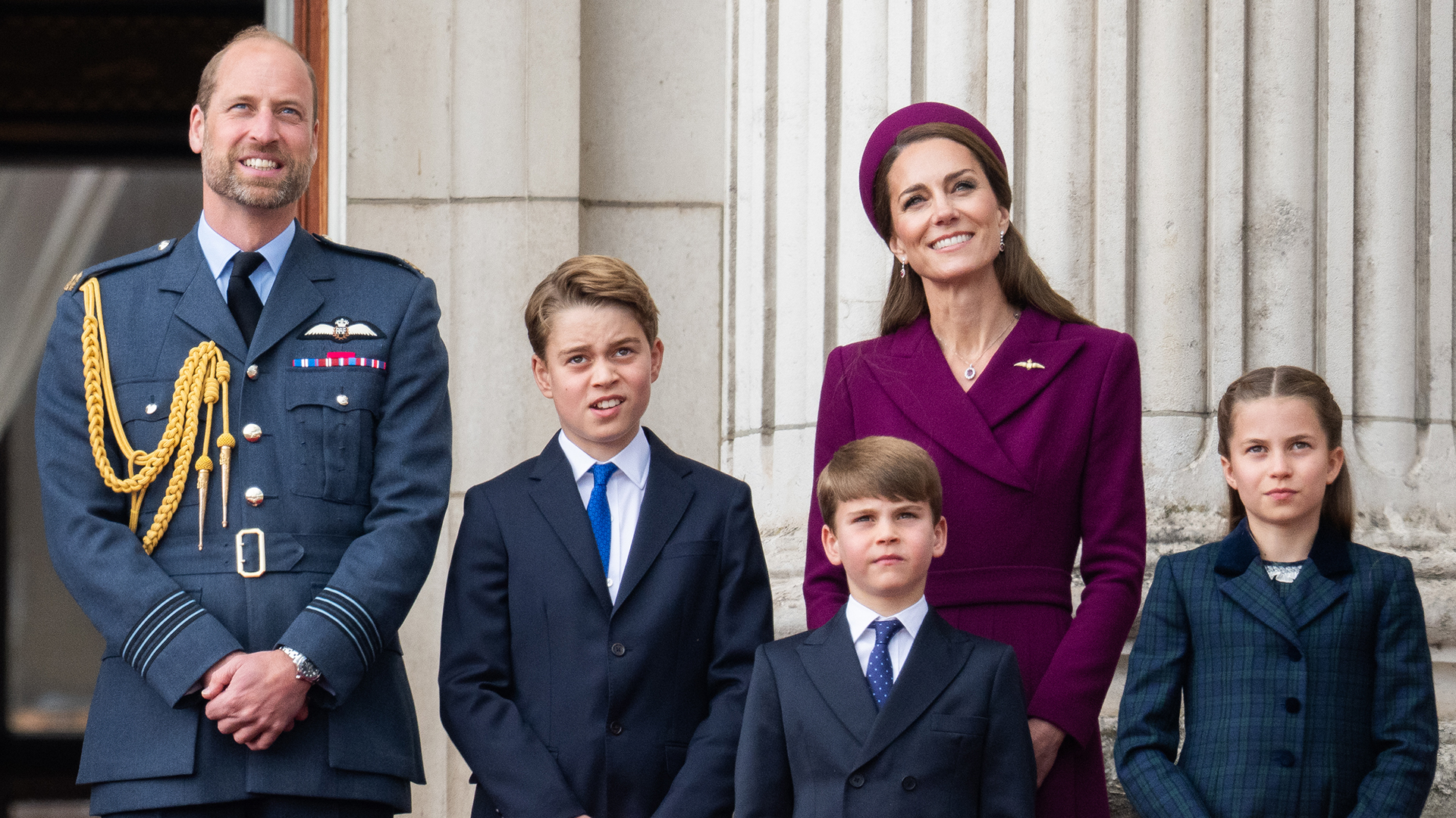 Prince William and Princess Kate are seen with Prince George, Prince Louis and Princess Charlotte on the balcony of Buckingham Palace wearing suits and dress coats at the 80th anniversary VE Day commemorations.