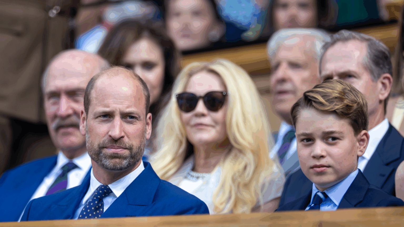 Prince George and Prince William sitting in the stands wearing blue suits at Wimbledon