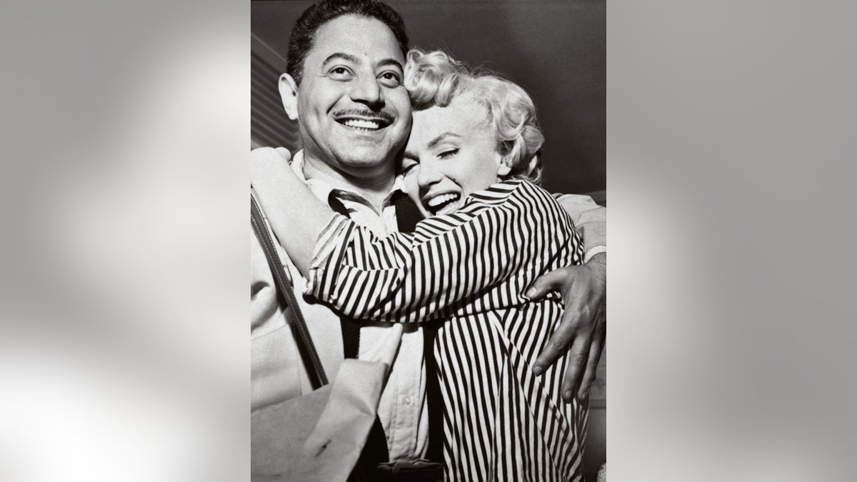 Marilyn Monroe laughing and embracing Sam Shaw.