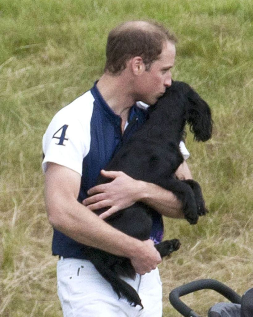 Prince William carrying his dog Lupo who he is kissing on the head