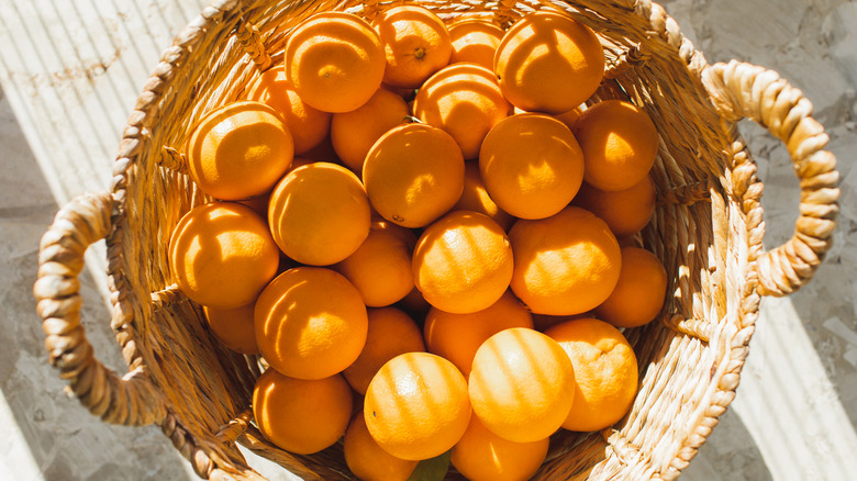 Ripe oranges are displayed in a woven wicker basket