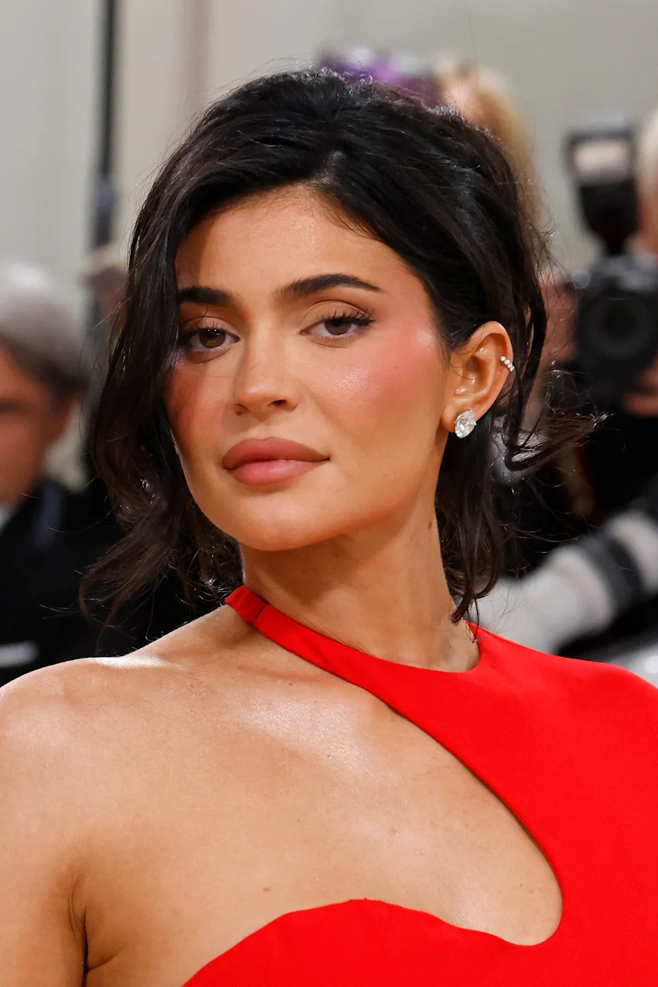 Person on the red carpet wearing an elegant, asymmetrical gown with a subtle expression