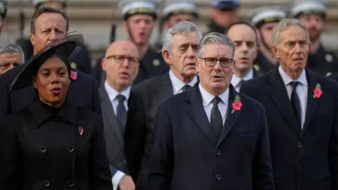 Reuters Kemi Badenoch and Keir Starmer standing in front of David Cameron, Gordon Brown and Tony Blair. They are all dressed in dark clothing and wearing poppies