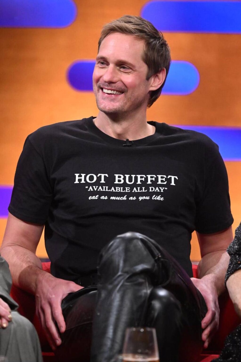 Alexander Skarsgård wore leather pants and a t-shirt that reads ‘Hot Buffet “Available All Day” eat as much as you like’ while on ‘The Graham Norton Show’. Styled by Harry Lambert. (November 27, 2025)