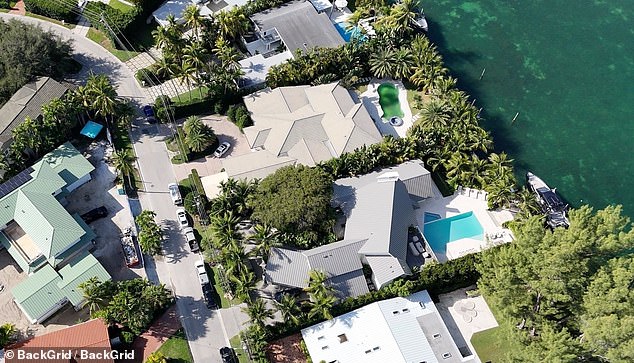The home in Miami's swanky Surfside neighborhood boasts a spacious property adorned with palm trees, its own boat slip and a green pool