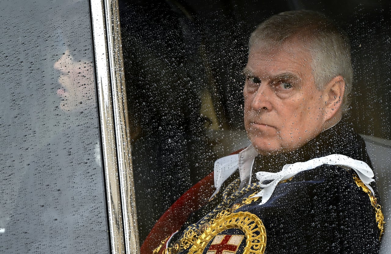 A person looks out a vehicle window with raindrops on it.