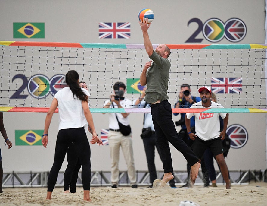 People play beach volleyball as other people watch.