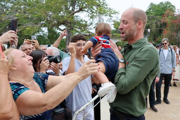 Prince William catches a baby who is thrust into his arms on a visit to Paqueta island in Brazil today