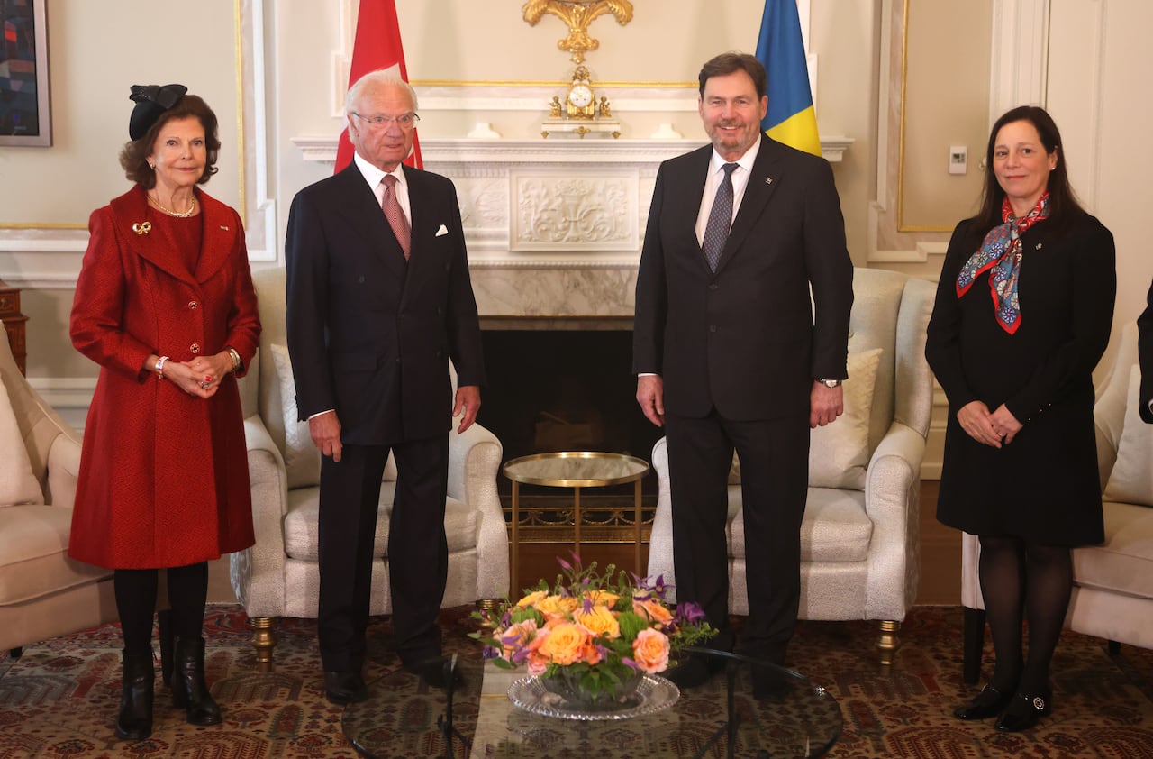 Two men and two women stand and pose for a photo in front of chairs.