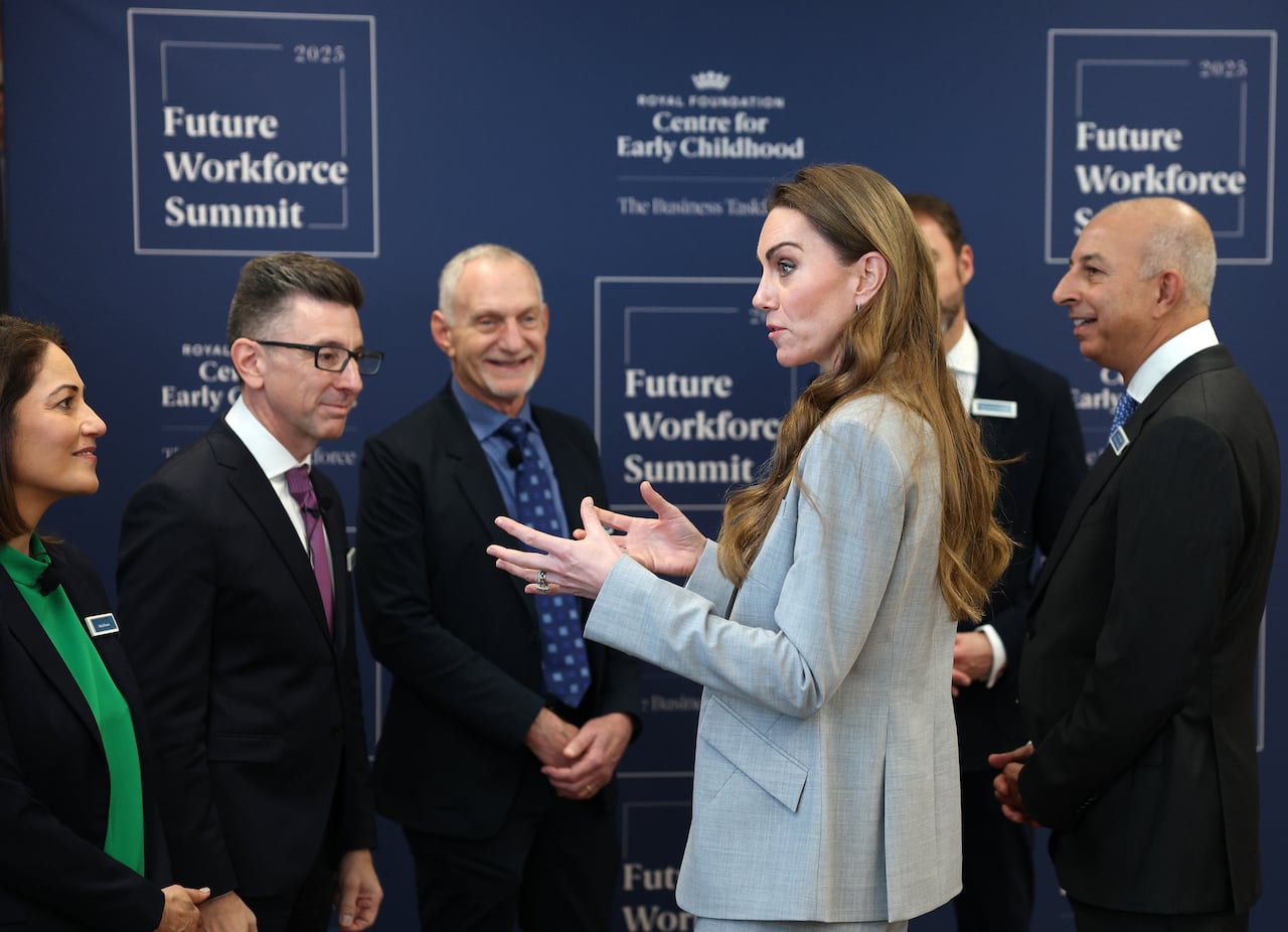 Several people stand near one another as one person speaks.
