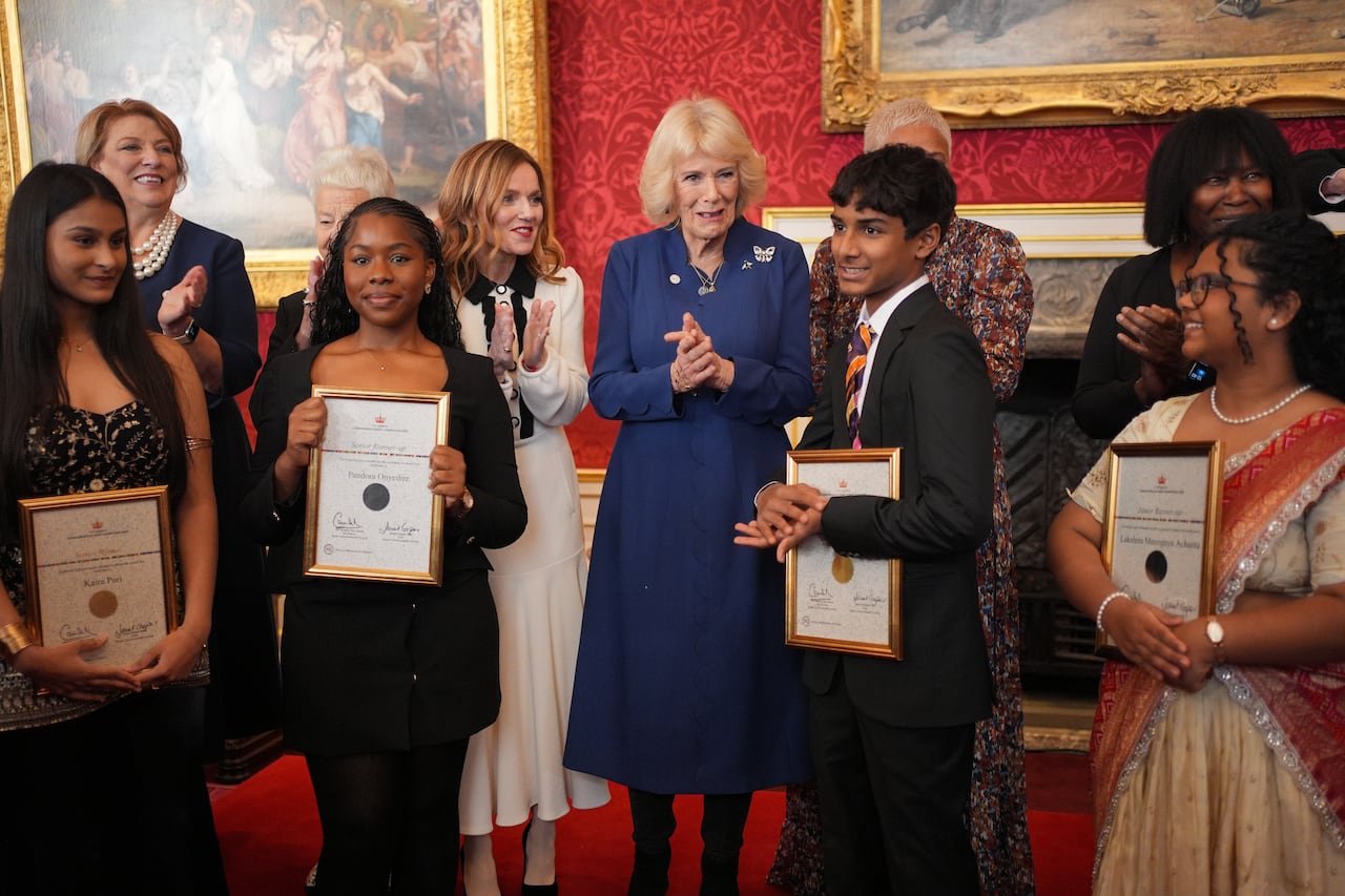 An adult stands with several children and other adults.
