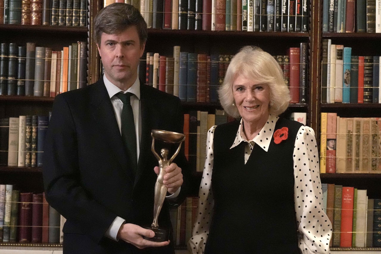 Two people stand side by side while one holds a trophy.