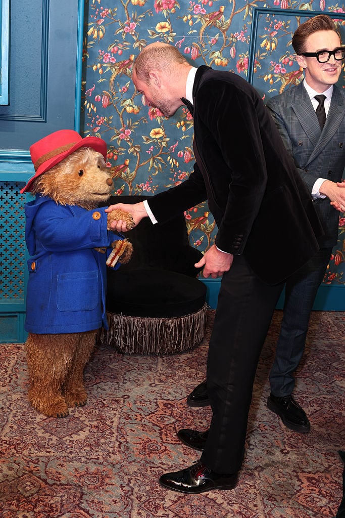 An adult shakes with a character dressed as a bear.