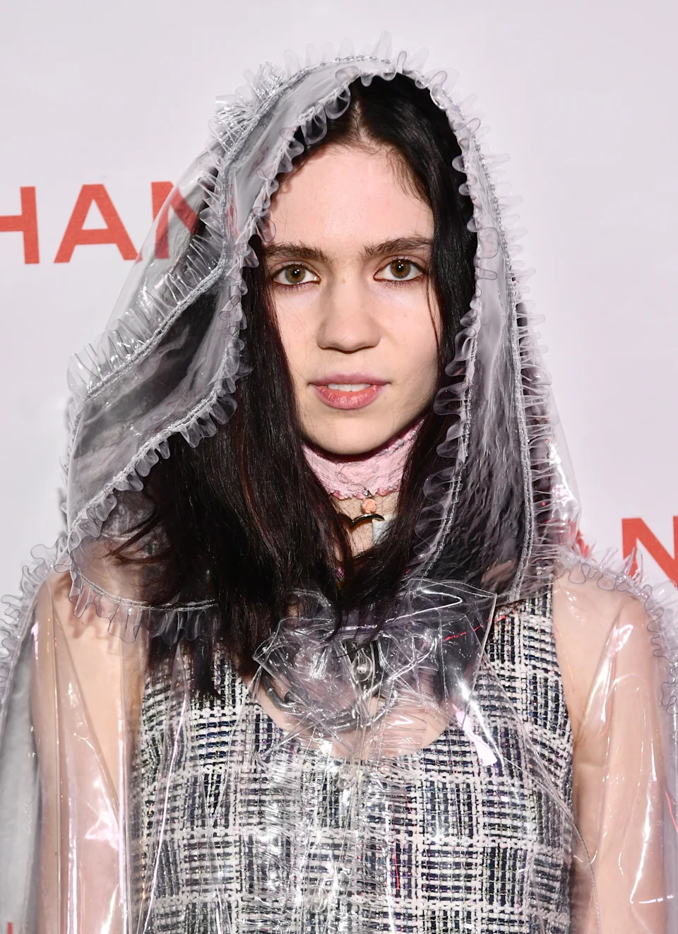 Person wearing a sheer, hooded garment over a textured dress at a formal event