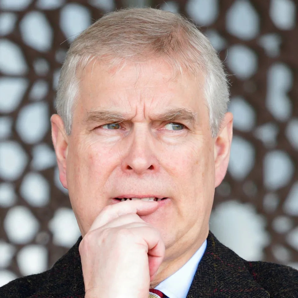  Prince Andrew wearing a black coat and looking anxious . 