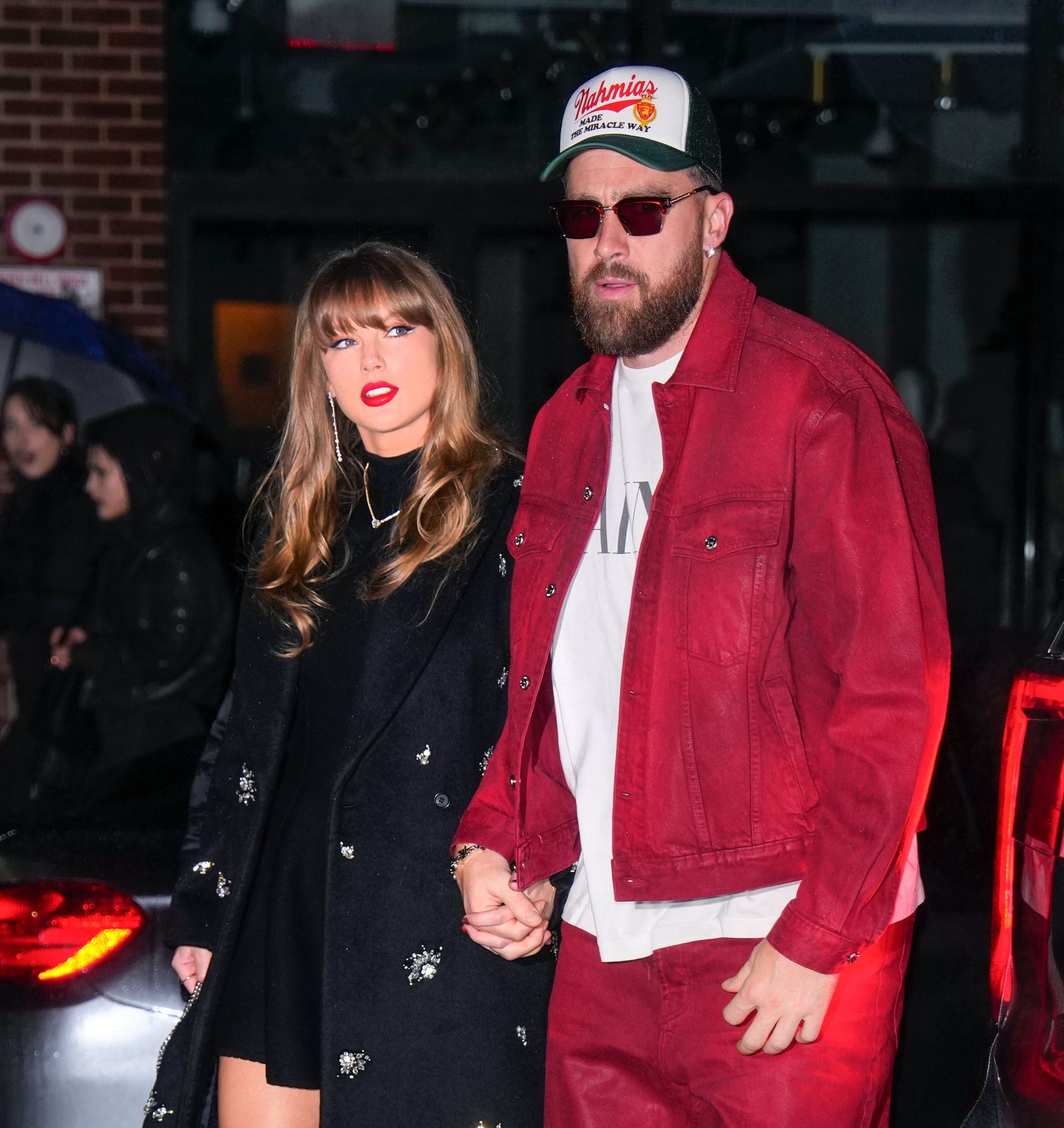 Image may contain Travis Kelce Taylor Swift Adult Person Clothing Coat Jacket Hat Body Part Hand and Photobombing