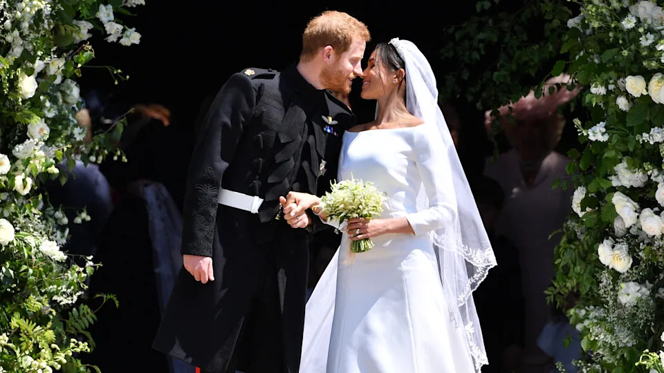 Prince Harry, Duke of Sussex kisses Meghan, Duchess of Sussex as they leave from the West Door of St George's Chapel, Windsor Castle on their wedding day in 2018