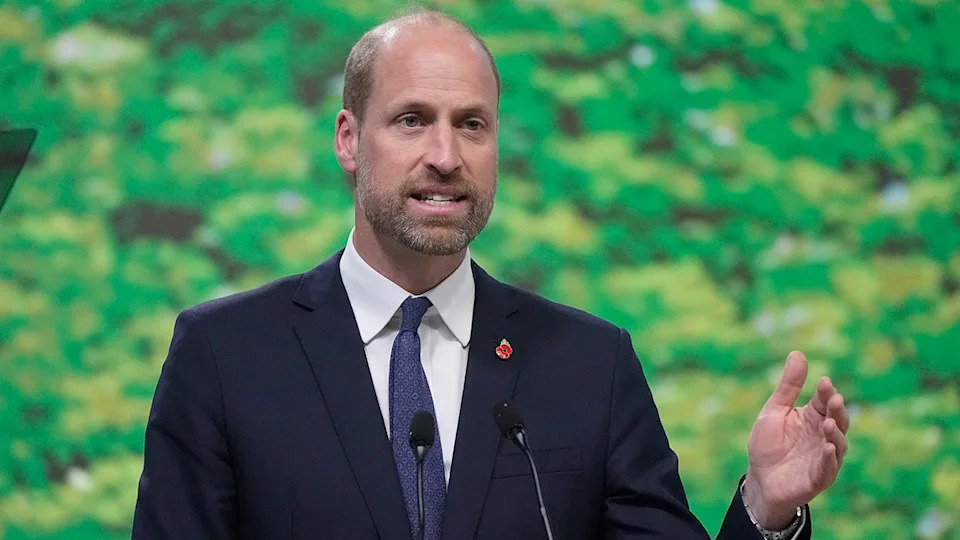 Prince William in a dark blue suit speaking from a podium.