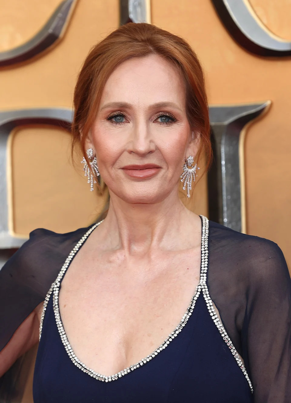 Person in elegant dress with jeweled neckline and sheer, flowing sleeves, posing at an event