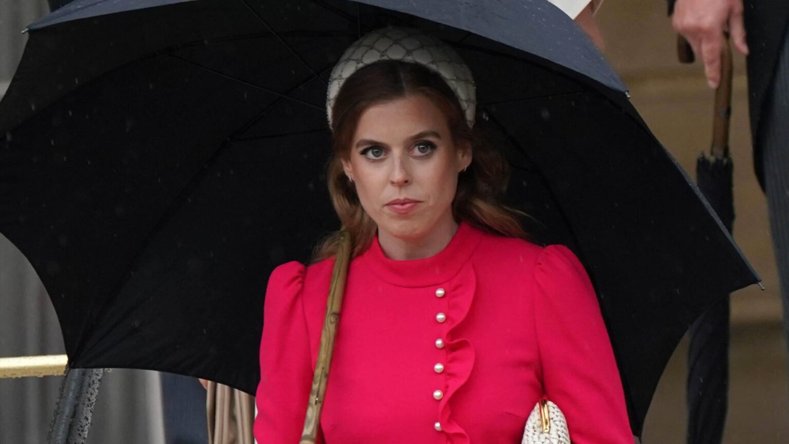 Princess Beatrice Felt Lonely During Preterm Baby Pregnancy Princess Beatrice wears a red dress and carries a black umbrella while walking in front of sister Princess Eugenie at the Sovereign's Garden Party at Buckingham Palace on May 21, 2024