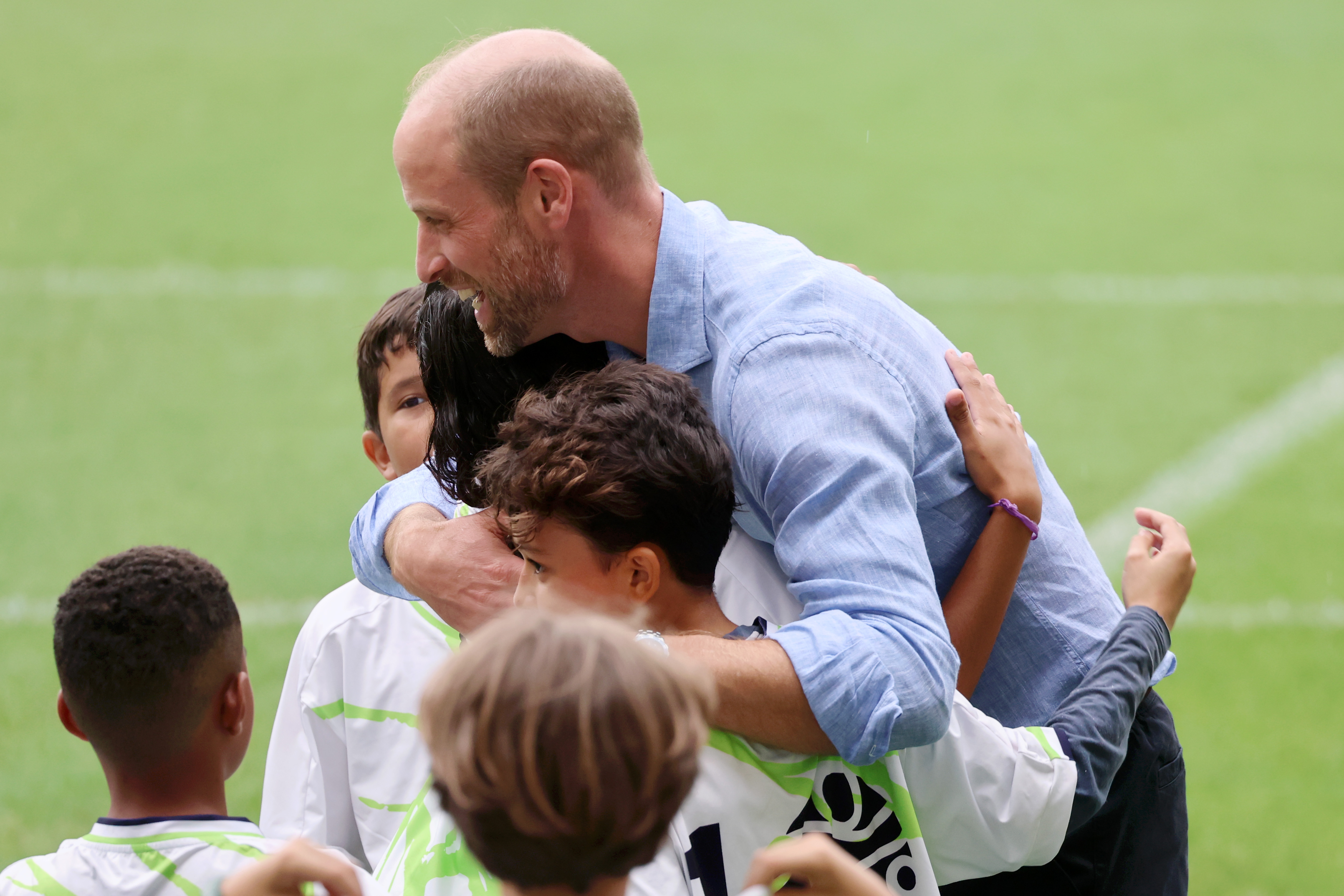 Prince William hugging children on a soccer field