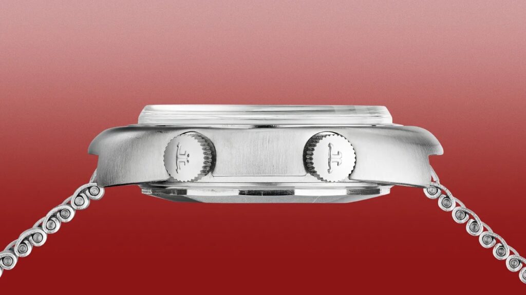 Side view of a silver metal watch case with two crowns and a linked metal bracelet against a red gradient background.