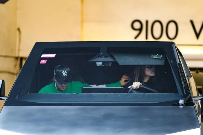 Justin Bieber rests his arm on Hailey Bieber's armrest as she drives out of a parking garage