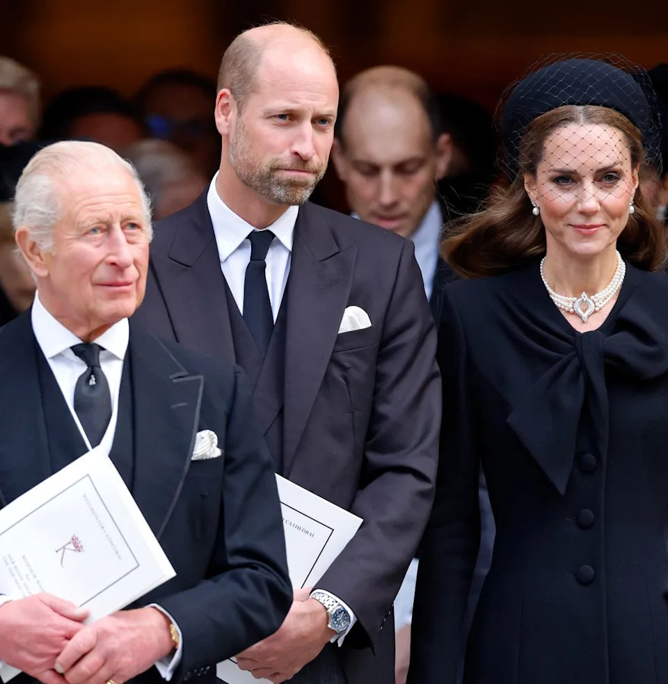  King Charles, Prince William and Princess Kate standing in a row wearing black outfits at the Duchess of Kent's funeral. 