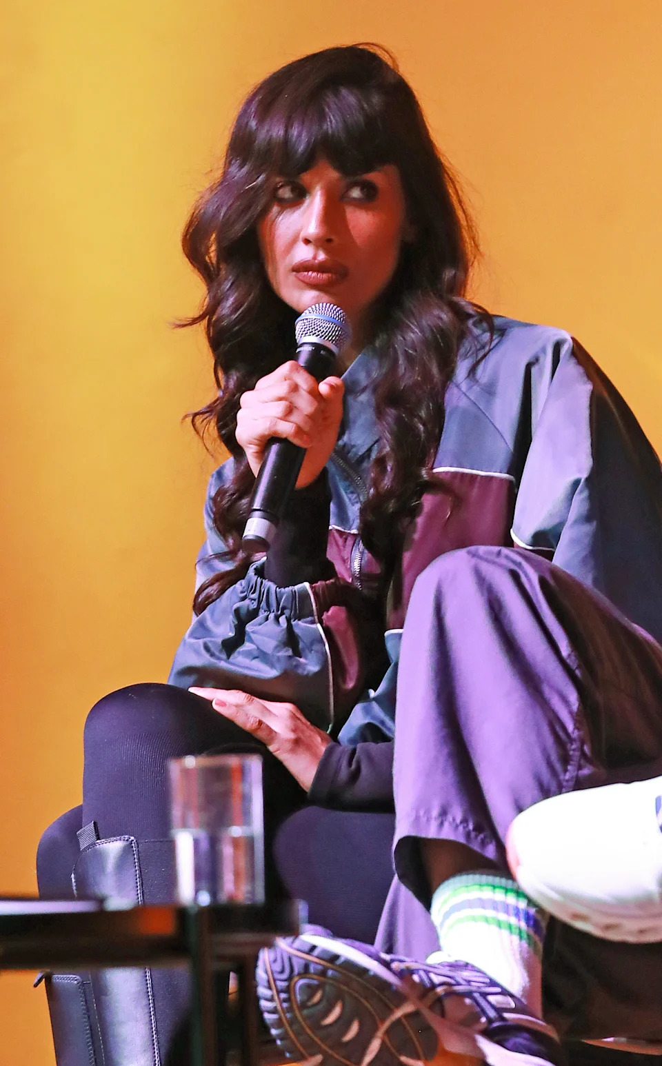 Jameela seated on stage, holding a microphone