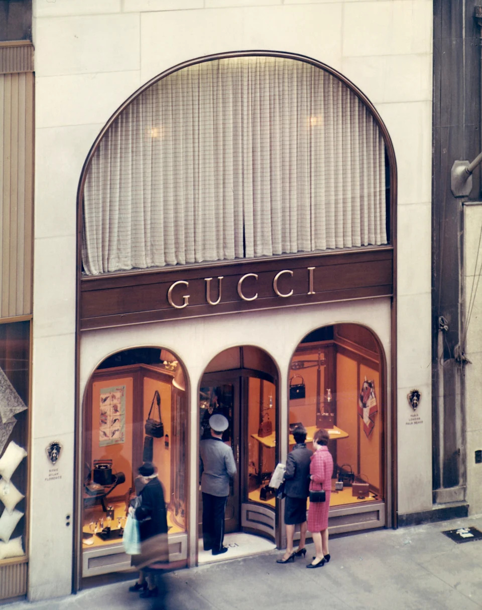 People window-shopping at a vintage Gucci store with elegant displays of handbags and accessories