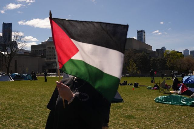 A protester holds up a Palestinian flag at an encampment set up on the University of Toronto campus on Thursday, May 2, 2024. THE CANADIAN PRESS/Chris Young