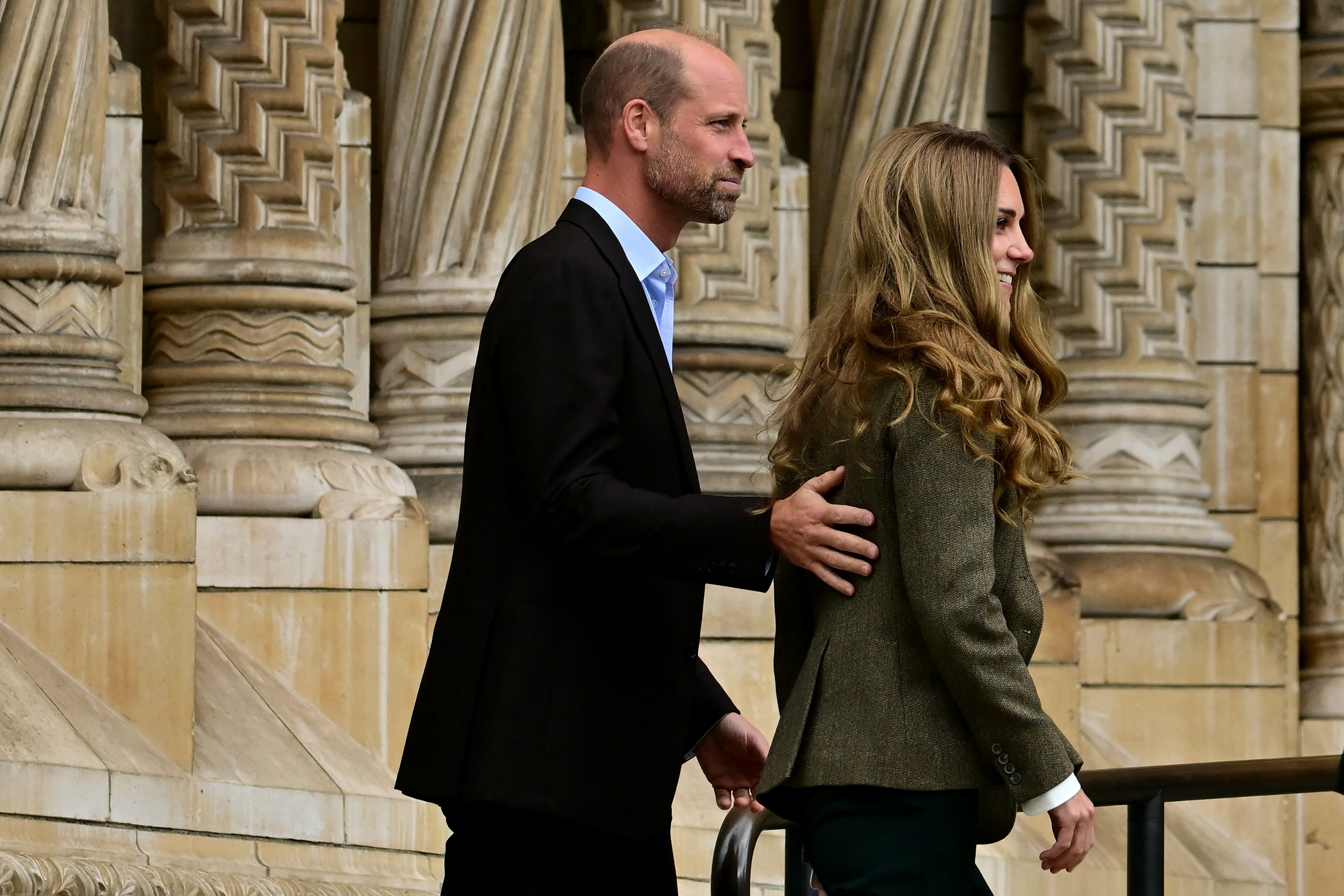 Prince William putting his hand on Kate Middleton's back outside a museum