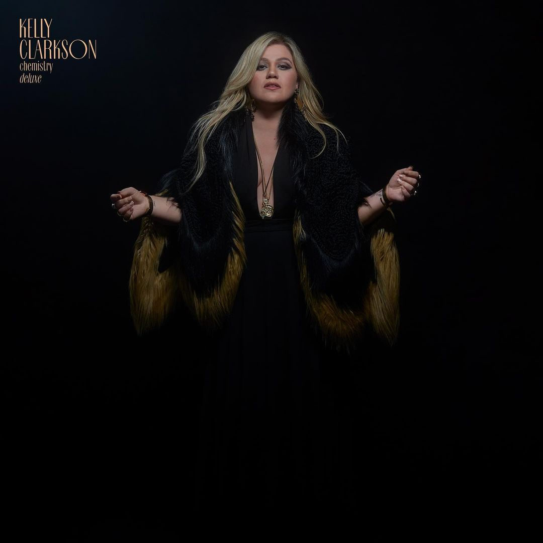 Kelly Clarkson wearing a black dress and a fur-trimmed stole for her album "Chemistry Deluxe."