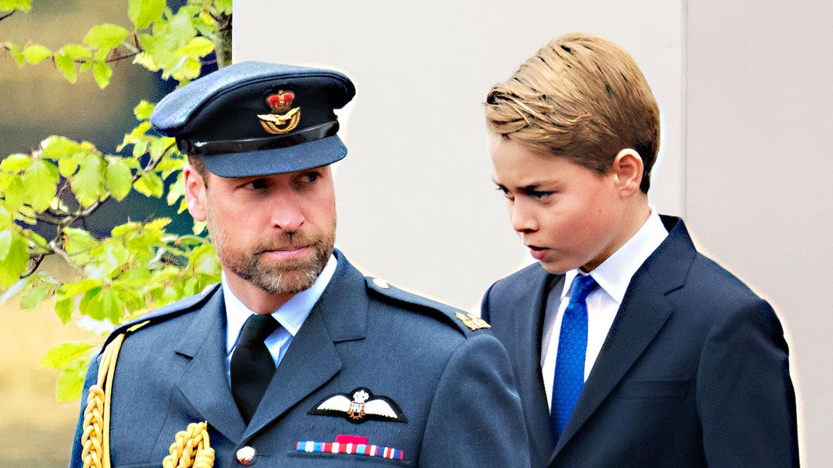 Prince William walking ahead of Prince George in uniform.