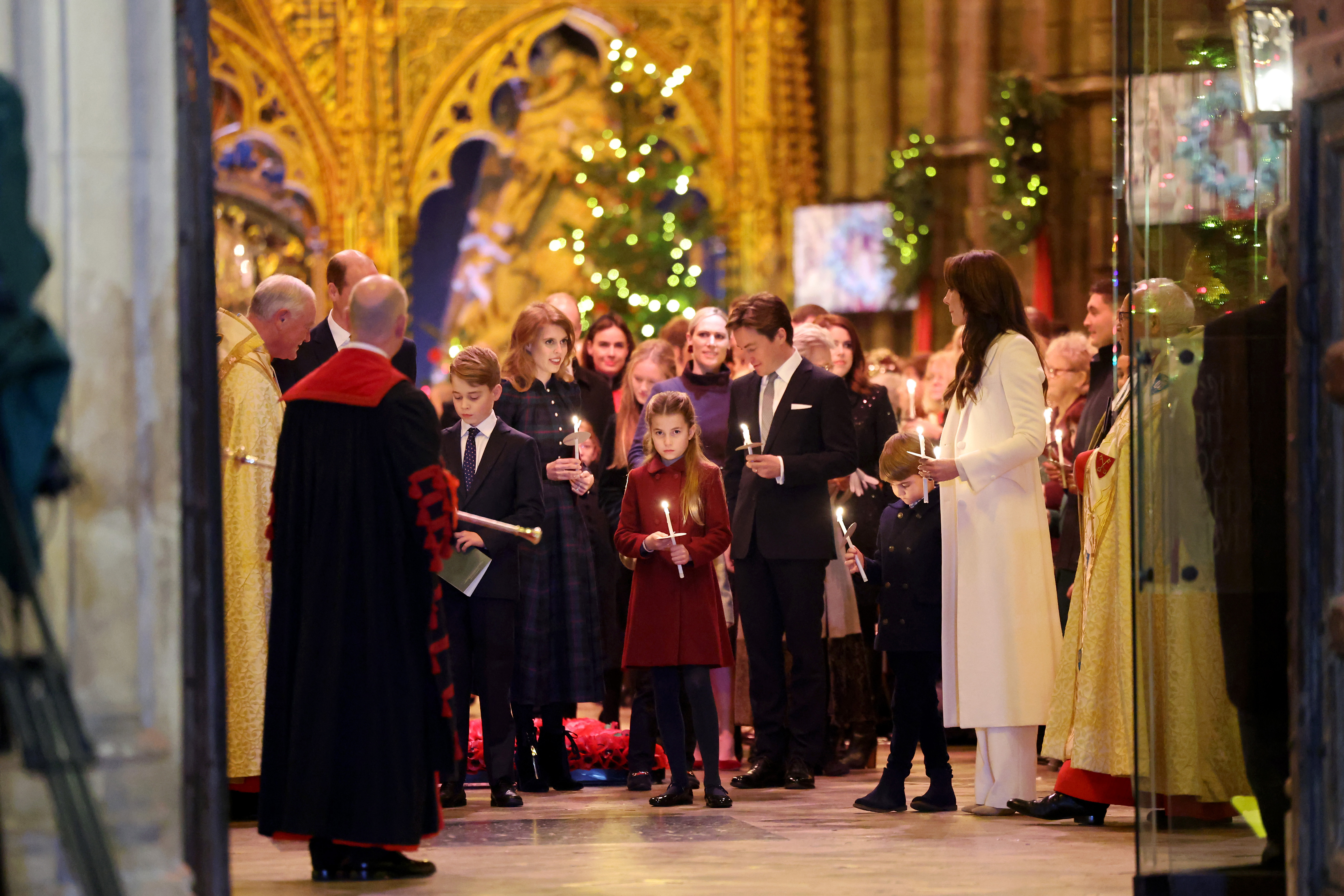 Princess Charlotte standing with Princess Kate, Prince Louis, Prince George, Princess Beatrice and other members of the Royal Family in Westminster Abbey holding a lit candle