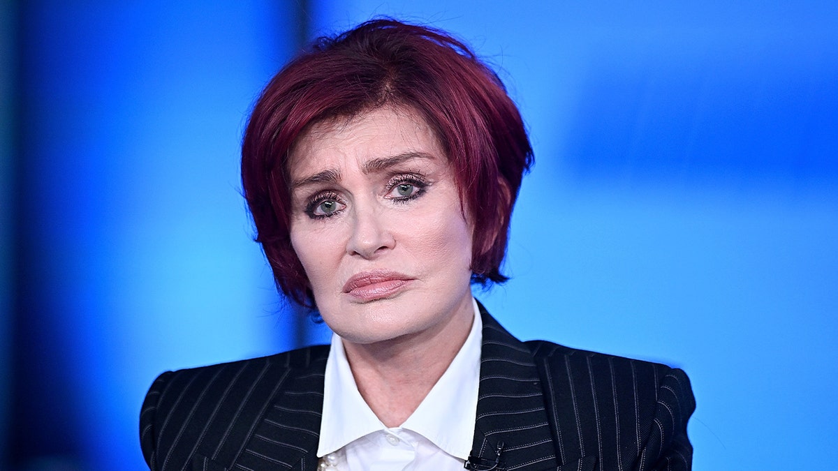 Sharon Osbourne looks somber in a pinstripe suit.