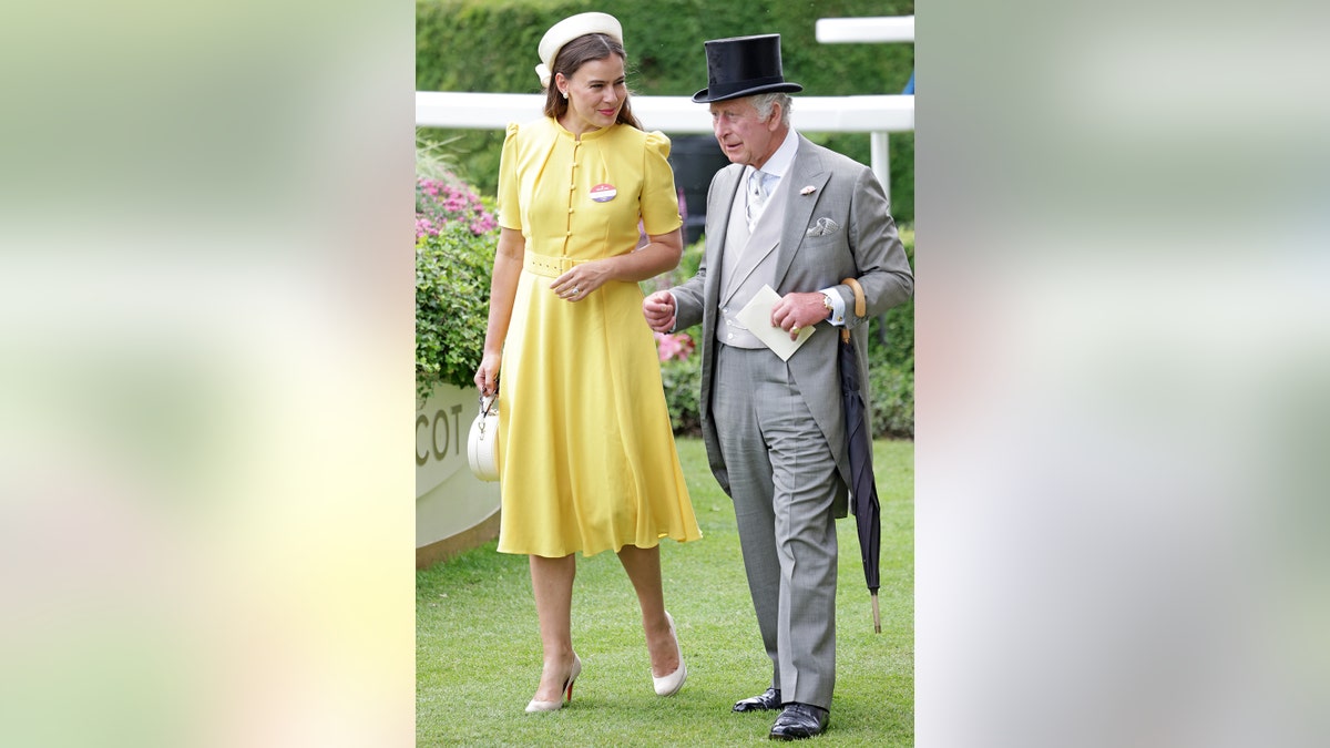 Sophie Winkleman in a yellow dress walking alongside King Charles.