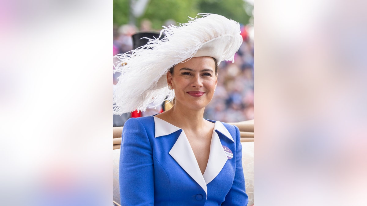 Sophie Winkleman wearing a blue and white dress with a matching white feather hat.