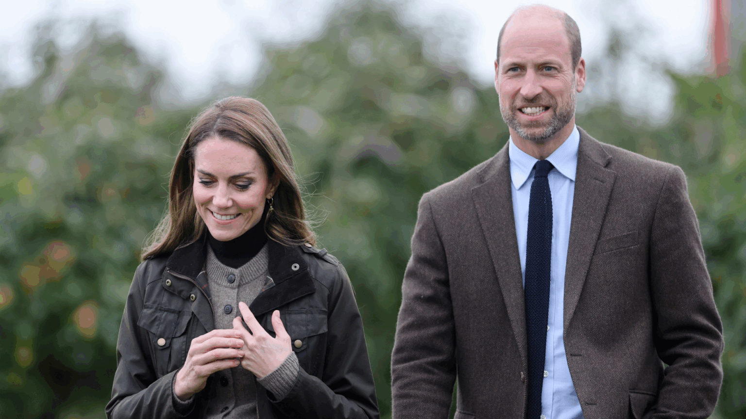 Prince William and Princess Kate Will Likely Avoid Announcing One Major Decision Until the “Eleventh Hour” to Avoid “Intense Scrutiny” Prince William and Kate Middleton wearing brown and green jackets walking through a field
