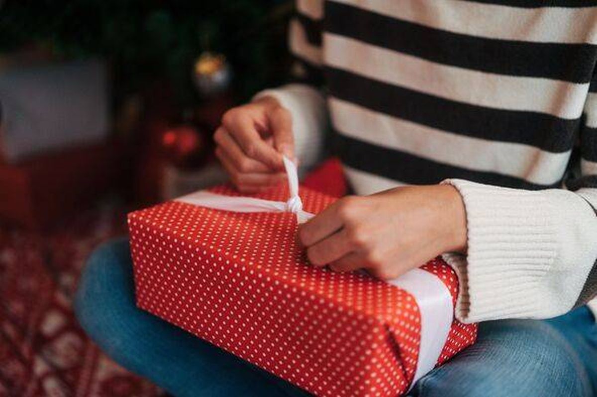 Woman wrapping christmas gift with festive ribbon