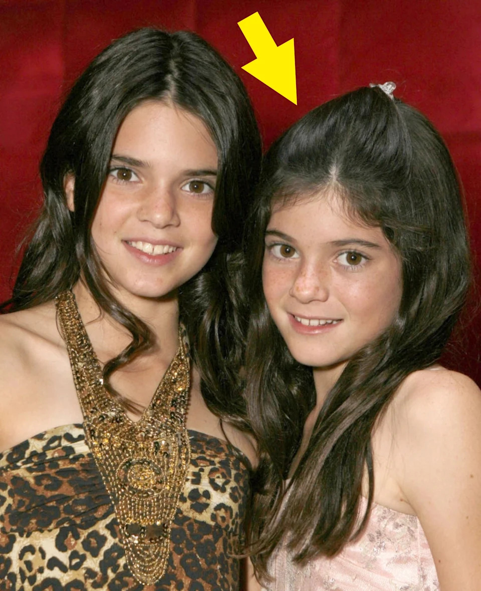 Two young individuals on the red carpet, one in a leopard print dress with a large necklace, the other in a light dress with a small hair accessory